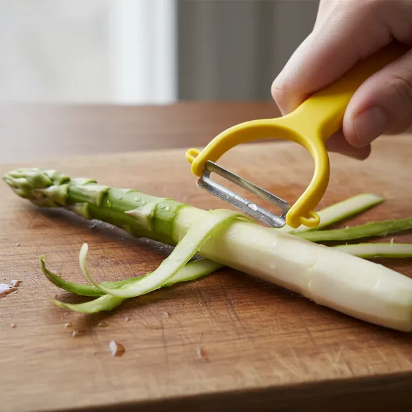 A hand holding an asparagus stalk on a cutting board, using a Y-peeler to remove the tough outer skin.